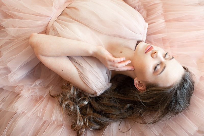 Dr. Allan Wulc Face Lift Review Woman Lightly Toucjing Her Face Laying Down in a Pink Dress