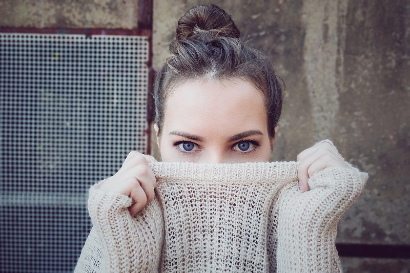Dark Circles Under the Eyes at Home Remedies woman Wearing a Sweater Holding the Neck Line Up to Cover Half of Her Face