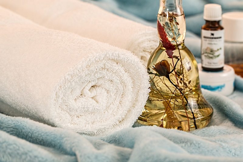 Tips to Reduce Facial Redness a Bottle of Essential Oils Next to a Rolled Up Towel