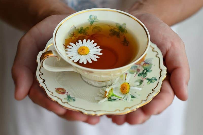 Tips to Reduce Facial Redness a Person Holding a Cup of Tea with a Flower Inside