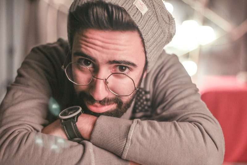 What are Dark Circles and how can I Treat them Close Up of a Man Resting His Face on His Crossed Arms Wearing a Beanie and Glasses